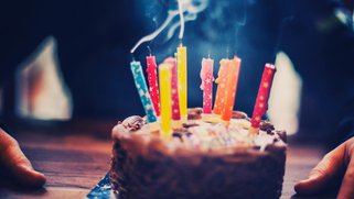 A small cake with candles blown out - smoke coming off the colorful candles