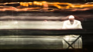 Picture of the Pope seated at a table praying