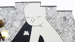 Artwork on the side of a building of a person looking under a curtain with buildings drawn on it.