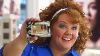 Picture of a woman holding a driver's license up to her face, smiling, from the movie Identity Thief.