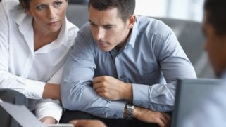 Picture of a sales team looking at a piece of paper and discussing it.