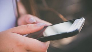 Closeup picture of a person's hand holding a cell phone.