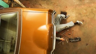 Picture of a person working underneath a car repairing it.