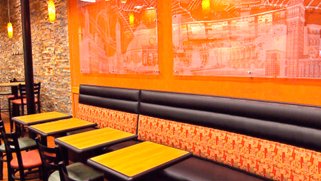 Photo inside a DiPasqua owned Subway restaurant showing tables, a bench, and glass artwork on the wall.