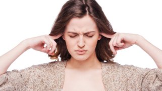 A women with her eyes closed and her fingers in her ears.